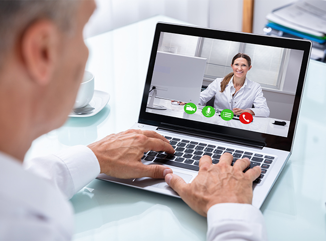 Ein Arzt und eine Ärztin tauschen sich per Telemedizin im Video-Chat miteinander aus.