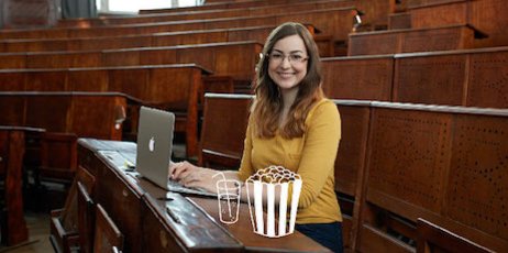 Frau sitzt in einem Hörsaal mit ihrem Laptop mit einer Zeichnung von Popcorn