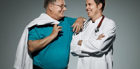 Ein Vater und sein Sohn stehen nebeneinander und tragen Arztkittel.