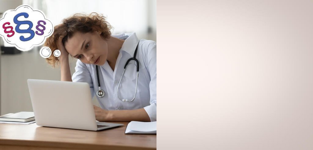 Eine Ärztin sitzt nachdenklich am Laptop und stützt ihren Kopf auf ihre rechte Hand. 