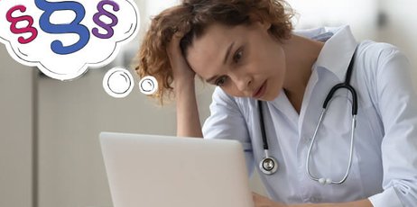 Eine Ärztin sitzt nachdenklich am Laptop und stützt ihren Kopf auf ihre rechte Hand. 
