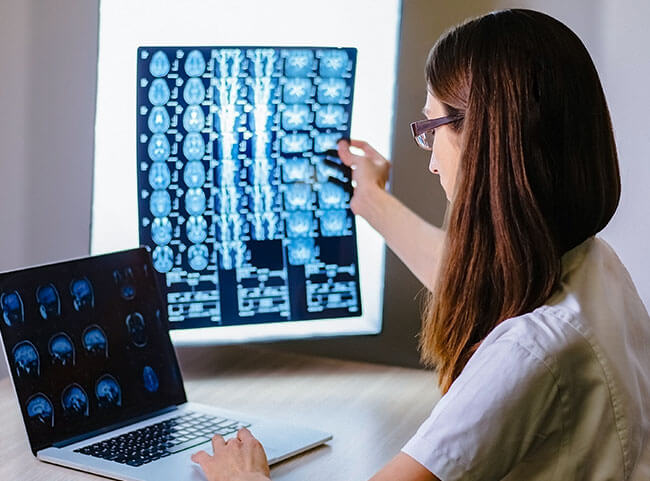 Eine Ärztin gleicht MRT-Aufnahmen mit Daten auf ihrem PC ab.