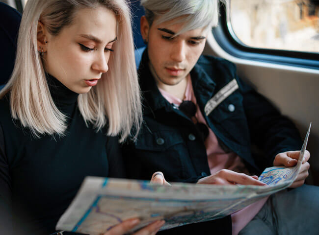 Ein Mediziner-Paar reist in einem Zug und blickt auf eine Stadtkarte.