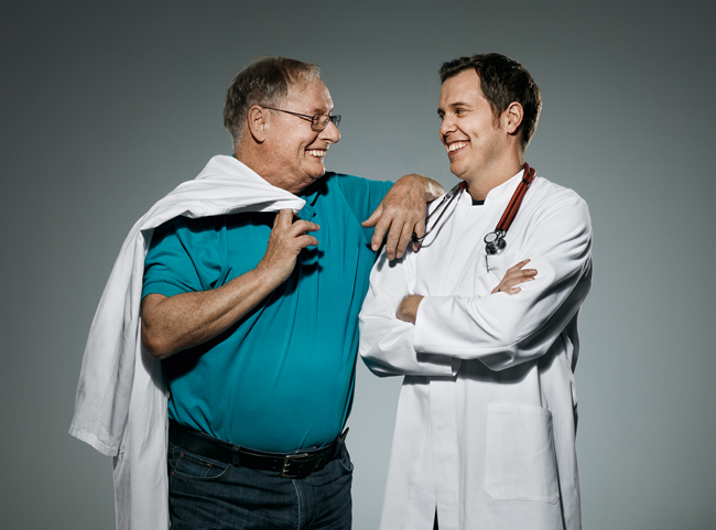 Ein Vater und sein Sohn stehen nebeneinander und tragen Arztkittel.