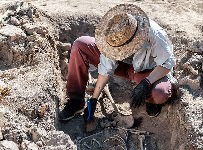 Eine Archäologin gräbt ein Fundstück an einer archäologischen Stätte aus.
