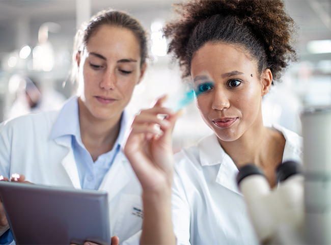 Zwei junge Medizinstudierende stehen im Labor und betrachten ihre Forschungsergebnisse.