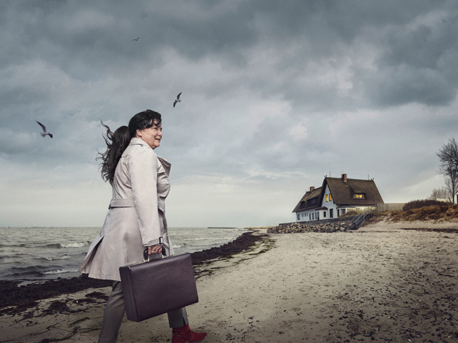 Plakat mit einer Frau und einem Koffer an der Küste