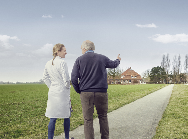 Ein Mann spricht mit einer Frau in einem weißen Kittel, während sie auf dem Land spazieren